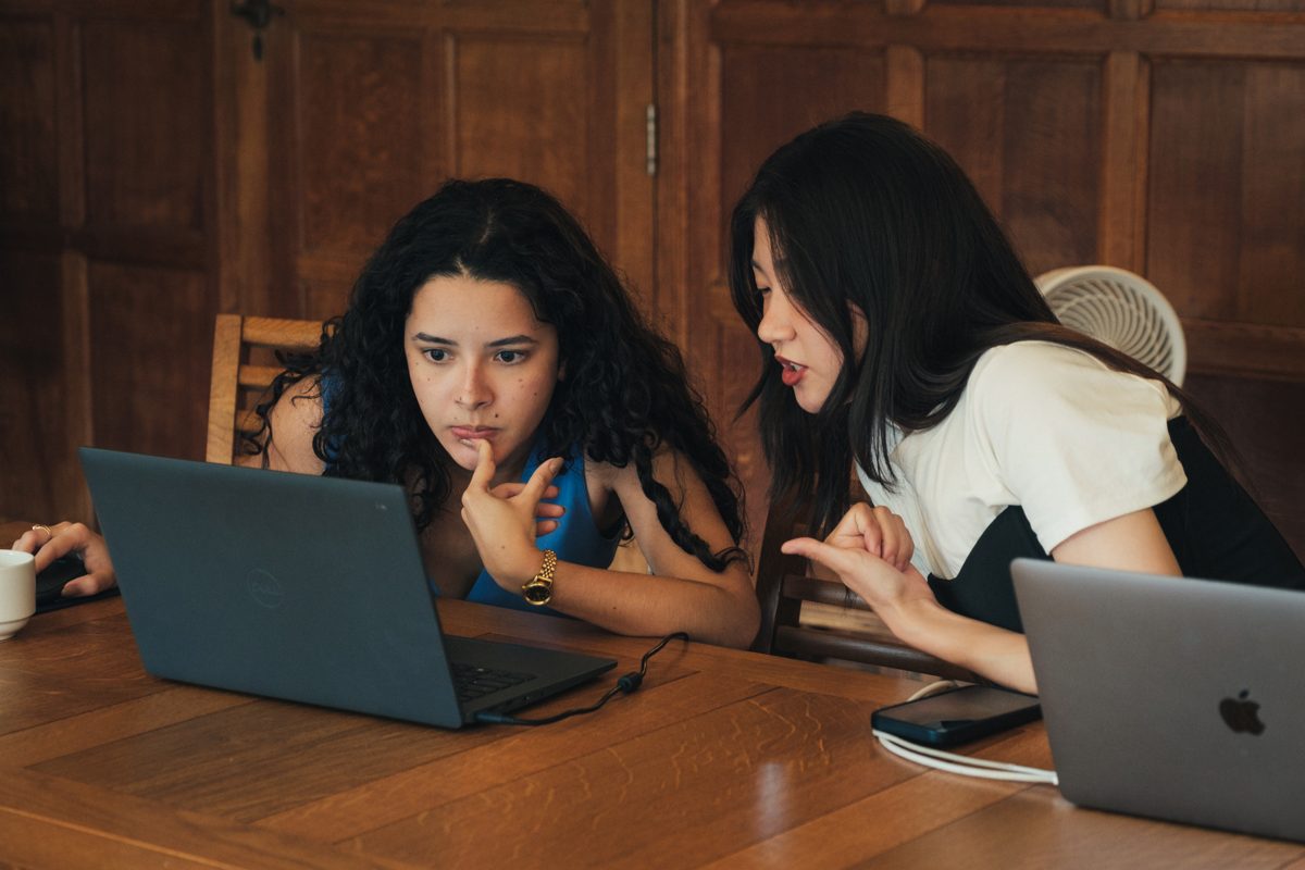 Two participants working through notebooks on a laptop